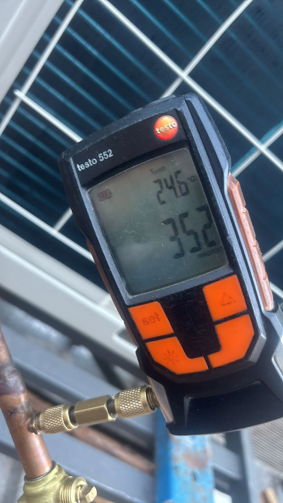 Instrumento digital testo 552 medindo pressão e temperatura em tubulação de cobre durante serviço de refrigeração.